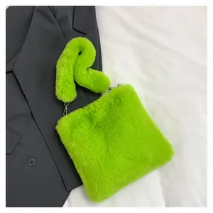 Dettaglio borsa shopper in ecopelliccia verde lime abbinata a un blazer grigio.