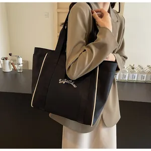 Bolso tote de nylon negro de primera calidad llevado por una modelo en oficina.