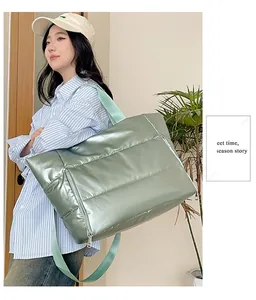 Large light green padded travel bag shown carried by a model in a lifestyle setting
