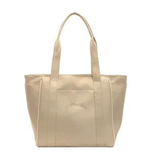 Vista frontal de un elegante bolso tote de nailon beige con bordado para oficina