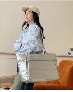 Model carrying a large silver padded travel shoulder bag in a lifestyle setting