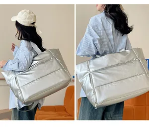 Large silver puffer travel tote bag shown on model for short trips and fitness use
