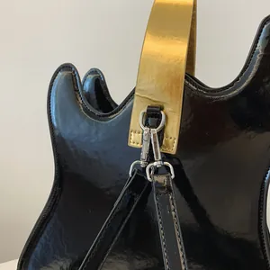 Detail shot of creative guitar-shaped bag featuring gold strap and glossy finish