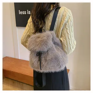 Close-up view of grey fluffy faux fur drawstring backpack worn by model in cozy sweater