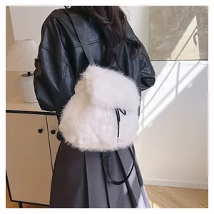 Detail view of a fluffy white faux fur backpack worn by a model in a black jacket