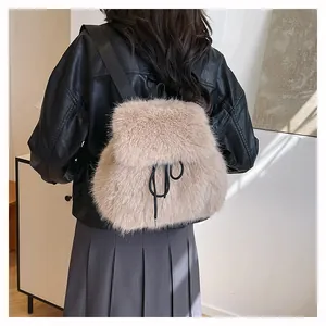 Back view of a model wearing a fluffy beige faux fur backpack with drawstrings