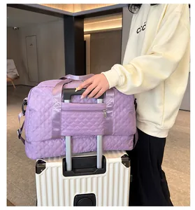 Detailed view of the purple quilted duffel bag with trolley sleeve on a white suitcase
