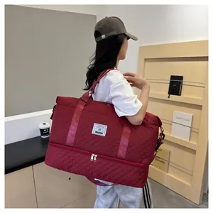 Detailed view of large burgundy quilted travel bag with shoe compartment on model
