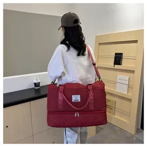 Large wine red quilted travel duffle bag with a separate shoe compartment shown in use