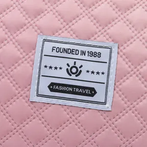Macro detail of premium pink quilted textile with 'Fashion Travel' brand label on bag