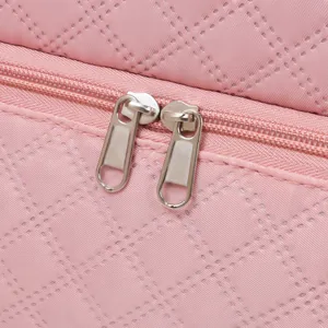 Detail shot of sturdy double metal zippers on pink rhombic quilted storage bag.