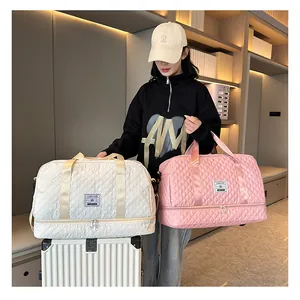 Pink and white quilted travel duffel bags held by a model with a suitcase