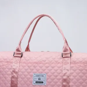 Detailed macro view of pink diamond quilted fabric and sturdy handles on travel bag