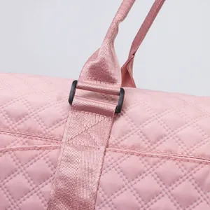 Macro detail of reinforced handle stitching and D-ring on pink quilted travel bag.