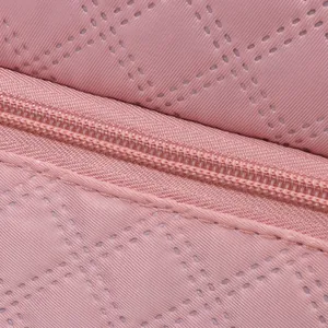 Detail shot of pink quilted fabric texture and high-quality zipper on travel bag