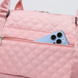 Close-up detail showing a functional exterior zipper pocket on a pink quilted gym travel bag.