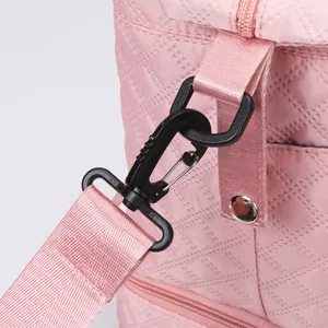 Close-up detail of black plastic swivel snap hook on a pink quilted travel bag strap.