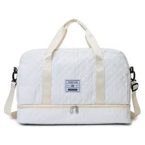 Front view of a white quilted travel bag featuring a double zipper bottom compartment