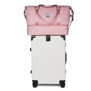 Large pink quilted travel bag with shoe compartment resting on top of a white suitcase