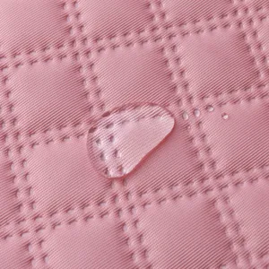 Close-up macro detail of pink quilted waterproof fabric showing a water droplet on surface