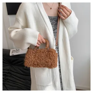 Close-up of brown fuzzy shearling handbag styled with a white knit cardigan