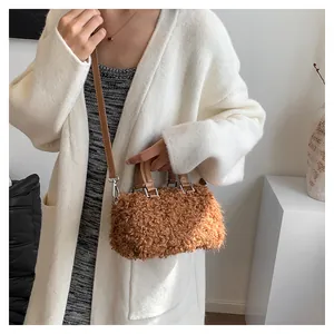 Detail view of brown fuzzy teddy handbag with leather strap on cream cardigan