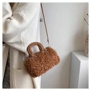 Close-up detail of a brown plush square handbag featuring textured faux fur and leather handle.