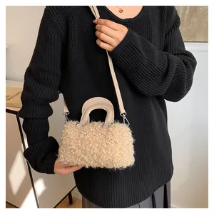 Detailed view of beige plush rectangular handbag worn with a black ribbed sweater