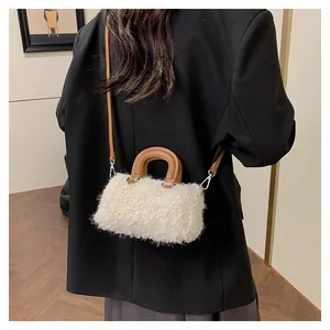 Back view of a white plush faux fur crossbody bag with brown leather accents.