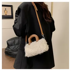 Detailed view of white plush rectangular handbag with brown crossbody strap on model