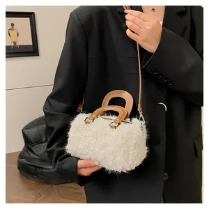 Detailed view of a white plush square handbag with brown handles and a black blazer.