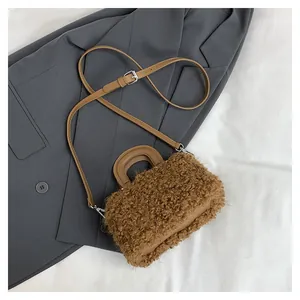 Detailed view of brown fluffy square handbag with smooth handle on gray blazer background