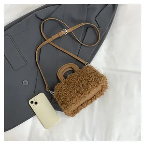 Detail view of brown plush square handbag with shoulder strap on a grey blazer