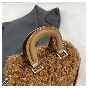 Close-up of brown fuzzy handbag with smooth tan leather handles and silver hardware.