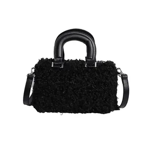 Frontal detail view of a black fluffy handheld bag with a leather handle and strap