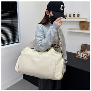Large cream travel duffel bag with shoulder strap carried by female model in lifestyle setting