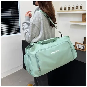 Side view of a large capacity light green travel duffel bag with shoulder strap.