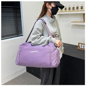 Model wearing a large capacity purple travel duffel bag for gym or weekend trips