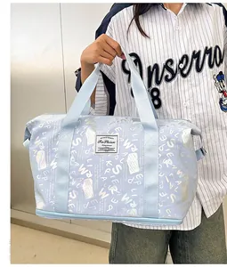 Vista detallada de bolsa de viaje azul claro con letras holográficas sostenida por modelo