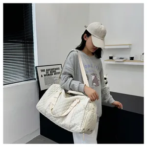 Detail view of a stylish white quilted gym duffel bag worn by a casual traveler