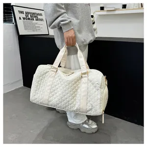 Lifestyle view of a person carrying a large white quilted travel duffel bag for gym or trips