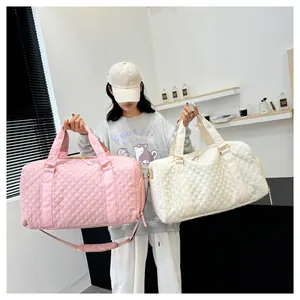 Model holding pink and cream quilted travel duffel bags for gym and travel