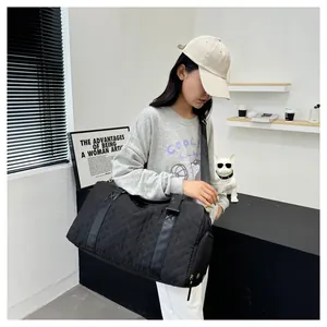 Model carrying a large black quilted duffel bag in a modern indoor lifestyle setting