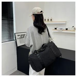 Stylish model carrying a large black quilted duffel bag suitable for gym and travel