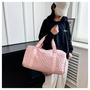 Pink quilted fitness and travel bag shown being carried by a model indoors.