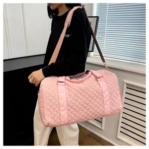 Stylish pink quilted travel duffel bag for gym and short trips carried by model