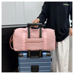 Detailed view of a pink quilted travel duffel bag secured onto a blue suitcase trolley handle