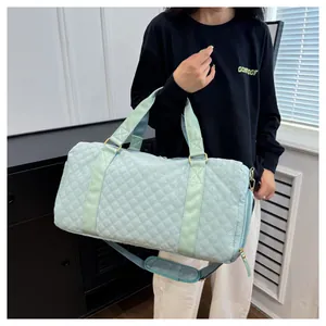 Light blue quilted gym duffel bag held by a person, showing its size and portability