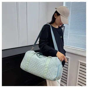 Lifestyle view of model carrying light blue quilted travel bag with shoulder strap