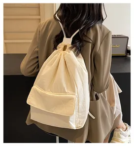 Back view of a minimalist cream white nylon drawstring backpack on a model in a blazer